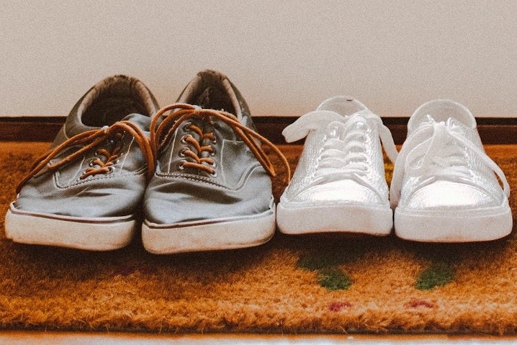 Floor mat with brown leather shoes and adjacent white sneakers