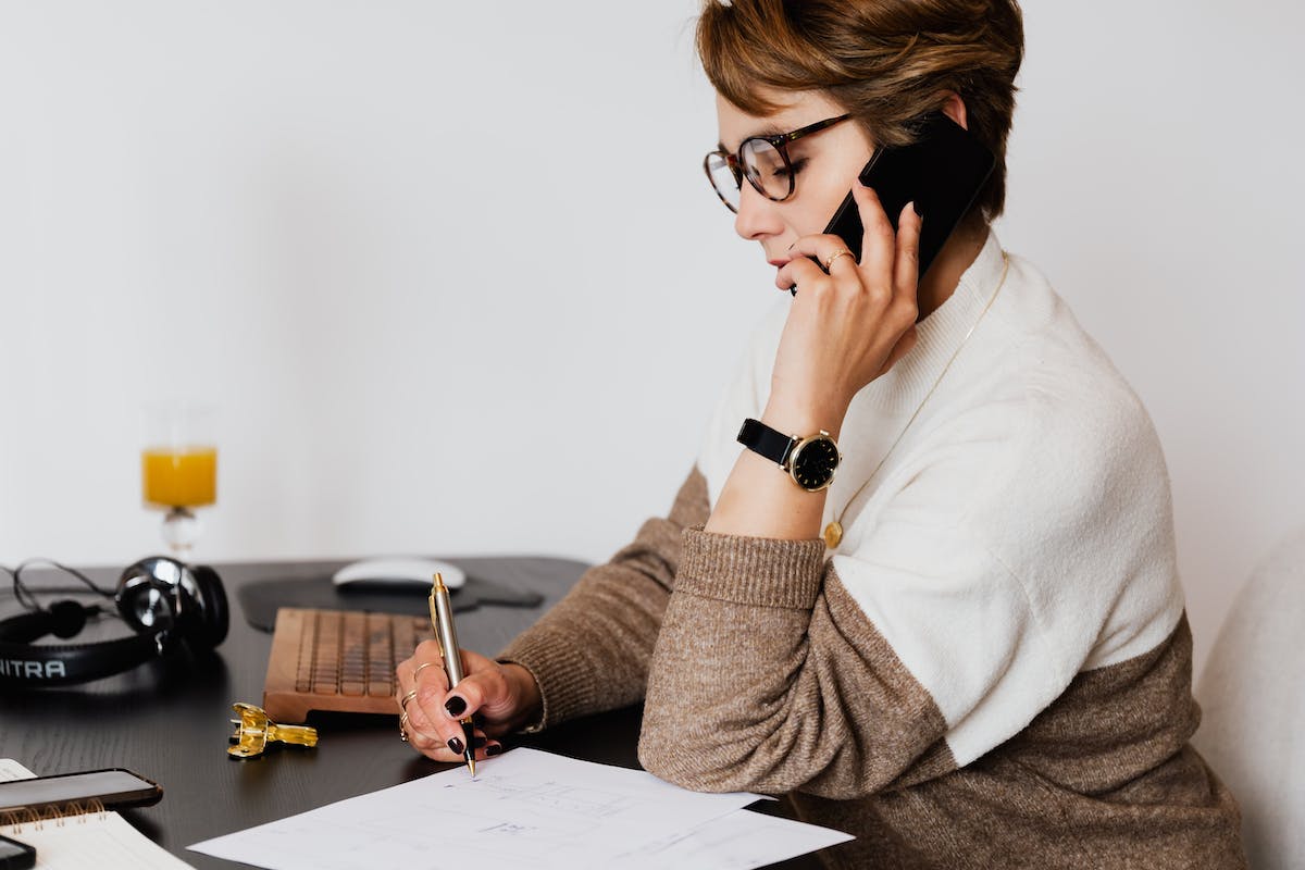 Woman with glasses taking notes during phone call