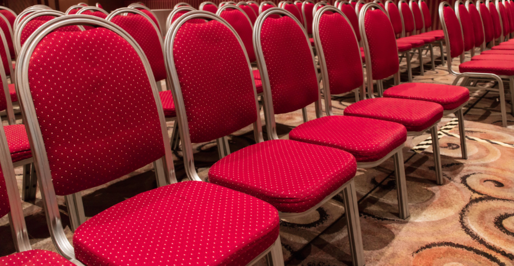 Rows of red upholstered metal chairs in large conference room