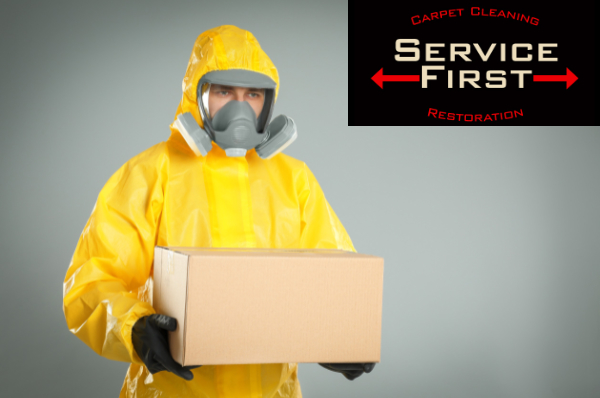 Man in yellow biohazard suit holding unmarked cardboard box