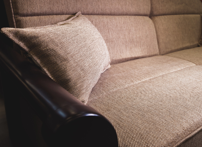 Beige corduroy sofa with matching throw pillow and mahogany wood arms and